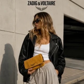 El bolso Rock Patchwork de Zadig & Voltaire es una de las versiones más especiales del icónico modelo Rock, reinterpretado en gamuza amarilla con diseño patchwork pespuntado, que le da textura, carácter y una estética única. Confeccionado en camurça (gamuza) de alta calidad, este modelo destaca por su aplicación frontal del logo de la marca con strass, aportando brillo y un contraste elegante con el acabado suave del material. Incorpora correas de hombro y crossbody envueltas en cadenas metálicas, desmontables mediante mosquetón, lo que permite llevarlo al hombro o cruzado según el estilo y la ocasión. Cuenta con cierre por solapa con imán, un bolsillo con cremallera en el interior de la solapa y un compartimento interno único, ideal para organizar lo esencial con comodidad. Su formato lo hace perfecto tanto para el día como para la noche, manteniendo siempre una estética sofisticada y urbana. Este modelo incluye dust bag original de la marca y corresponde a un producto seminuevo en excelente estado de conservación, con mínimos signos de uso, manteniendo intacta su estética y funcionalidad. Detalles del producto: – Marca: Zadig & Voltaire – Modelo: Rock Patchwork – Color: Amarillo – Material: Gamuza (camurça) – Diseño: Patchwork pespuntado – Detalle frontal: Logo con strass – Correas: Hombro y crossbody con cadena metálica, desmontables – Cierre: Solapa con imán – Compartimentos: Bolsillo interior con cremallera + compartimento único – Incluye: Dust bag original – Estado: Seminuevo, excelente conservación Medidas aproximadas: – Ancho: 27 cm – Alto: 14 cm – Profundidad: 3 cm – Altura correa hombro: 31 cm – Altura correa crossbody: 53 cm Producto original Zadig & Voltaire, cuidadosamente seleccionado por Trendstore Chile para mujeres que buscan piezas únicas, moda premium y diseño con identidad, disponible para venta en Chile.