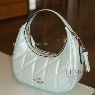 En Trendstore Chile te presentamos este bolso Coach confeccionado en cuero suave perlado, un material premium que combina suavidad, durabilidad y un acabado elegante. Su diseño práctico y moderno lo hace ideal para mujeres que buscan estilo y funcionalidad en un solo accesorio. Cuenta con un cierre superior de cremallera que mantiene tus pertenencias seguras, mientras que su interior forrado en tela incluye un bolsillo con cremallera para organizar tus esenciales. Las asas permiten llevarlo de manera cómoda en la mano, y la correa desmontable con caída de 59,7 cm ofrece la opción de usarlo al hombro o cruzado tipo crossbody según tu estilo. Medidas aproximadas: Largo: 19,7 cm Alto: 10,2 cm Ancho: 6,4 cm Caída de asas: 12,7 cm Caída de correa desmontable: 59,7 cm Materiales: Cuero suave perlado Forro interior de tela Características