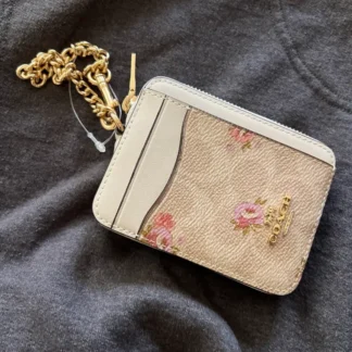 En Trendstore Chile te presentamos la Zip Card Case de Coach, un accesorio compacto y funcional que combina diseño elegante y practicidad. Confeccionada en Signature coated canvas, esta billetera ofrece resistencia y un acabado premium en un formato ultracompacto, ideal para caber en bolsos pequeños o incluso en el bolsillo. Cuenta con un bolsillo abierto, un compartimento con cremallera y dos ranuras para tarjetas, además de una ventana para identificación, manteniendo tus esenciales organizados y accesibles. Su correa de cadena con clip tipo dogleash añade un detalle metálico brillante y permite llevarla cómodamente en la muñeca. Medidas aproximadas: Largo: 7,6 cm Alto: 10,8 cm Ancho: 1,9 cm Materiales: Signature coated canvas Correa de cadena metálica Características principales: Modelo: Zip Card Case Style Number: CW883 Bolsillo abierto Compartimento con cremallera Dos ranuras para tarjetas Ventana para identificación Correa de cadena tipo muñequera Público: Mujer Un accesorio original Coach, seleccionado por Trendstore para mujeres que buscan una billetera compacta, funcional y de moda premium, disponible para venta en Chile.