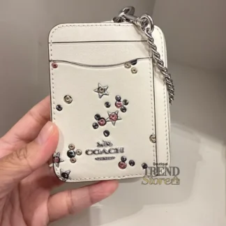 En Trendstore Chile te presentamos la Zip Card Case de Coach, un accesorio compacto y funcional que combina diseño elegante y practicidad. Confeccionada en Signature coated canvas, esta billetera ofrece resistencia y un acabado premium en un formato ultracompacto, ideal para caber en bolsos pequeños o incluso en el bolsillo. Cuenta con un bolsillo abierto, un compartimento con cremallera y dos ranuras para tarjetas, además de una ventana para identificación, manteniendo tus esenciales organizados y accesibles. Su correa de cadena con clip tipo dogleash añade un detalle metálico brillante y permite llevarla cómodamente en la muñeca. Medidas aproximadas: Largo: 7,6 cm Alto: 10,8 cm Ancho: 1,9 cm Materiales: Signature coated canvas Correa de cadena metálica Características principales: Modelo: Zip Card Case Style Number: CW883 Bolsillo abierto Compartimento con cremallera Dos ranuras para tarjetas Ventana para identificación Correa de cadena tipo muñequera Público: Mujer Un accesorio original Coach, seleccionado por Trendstore para mujeres que buscan una billetera compacta, funcional y de moda premium, disponible para venta en Chile.