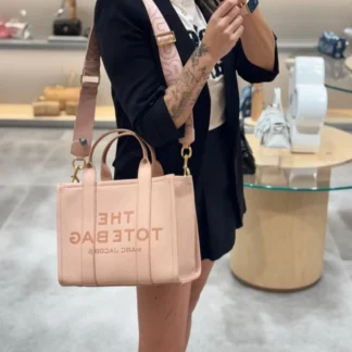 La Marc Jacobs The Tote Bag Mediana en cuero color rosa blush es uno de los modelos más icónicos y funcionales de la marca. Confeccionada en cuero de textura granulada, destaca por su diseño estructurado, moderno y atemporal, ideal para mujeres que buscan estilo y practicidad en un solo bolso. Este modelo cuenta con el logo en relieve en la parte frontal y un parche con el logo en la parte posterior, detalles que refuerzan su identidad original y de lujo. Sus dos asas superiores permiten llevarla cómodamente en la mano, mientras que la correa ajustable y removible para el hombro ofrece versatilidad para usarla cruzada o al hombro según tu rutina. El compartimento principal es amplio y funcional, con cierre superior que brinda mayor seguridad. En su interior incorpora bolsillos con cierre y múltiples compartimentos internos que facilitan la organización de tus esenciales. Gracias a su tamaño mediano, cabe computador, por lo que es perfecta para el trabajo, la universidad o jornadas largas fuera de casa. En Trendstore Chile encuentras esta Marc Jacobs The Tote Bag 100% original, con envío a todo Chile, atención cercana y stock actualizado. Un bolso versátil, elegante y pensado para acompañarte todos los días.