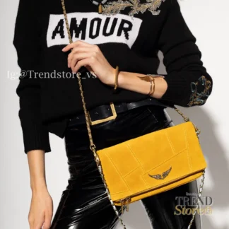El bolso Rock Patchwork de Zadig & Voltaire es una de las versiones más especiales del icónico modelo Rock, reinterpretado en gamuza amarilla con diseño patchwork pespuntado, que le da textura, carácter y una estética única. Confeccionado en camurça (gamuza) de alta calidad, este modelo destaca por su aplicación frontal del logo de la marca con strass, aportando brillo y un contraste elegante con el acabado suave del material. Incorpora correas de hombro y crossbody envueltas en cadenas metálicas, desmontables mediante mosquetón, lo que permite llevarlo al hombro o cruzado según el estilo y la ocasión. Cuenta con cierre por solapa con imán, un bolsillo con cremallera en el interior de la solapa y un compartimento interno único, ideal para organizar lo esencial con comodidad. Su formato lo hace perfecto tanto para el día como para la noche, manteniendo siempre una estética sofisticada y urbana. Este modelo incluye dust bag original de la marca y corresponde a un producto seminuevo en excelente estado de conservación, con mínimos signos de uso, manteniendo intacta su estética y funcionalidad. Detalles del producto: – Marca: Zadig & Voltaire – Modelo: Rock Patchwork – Color: Amarillo – Material: Gamuza (camurça) – Diseño: Patchwork pespuntado – Detalle frontal: Logo con strass – Correas: Hombro y crossbody con cadena metálica, desmontables – Cierre: Solapa con imán – Compartimentos: Bolsillo interior con cremallera + compartimento único – Incluye: Dust bag original – Estado: Seminuevo, excelente conservación Medidas aproximadas: – Ancho: 27 cm – Alto: 14 cm – Profundidad: 3 cm – Altura correa hombro: 31 cm – Altura correa crossbody: 53 cm Producto original Zadig & Voltaire, cuidadosamente seleccionado por Trendstore Chile para mujeres que buscan piezas únicas, moda premium y diseño con identidad, disponible para venta en Chile.