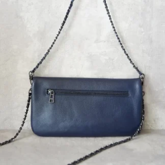 El bolso Rock Azul de Zadig & Voltaire es uno de los modelos más icónicos de la marca parisina, reconocido por su estética rock chic y su diseño urbano con carácter. Confeccionado en cuero de alta calidad en tono azul, es perfecto para quienes buscan un accesorio sofisticado pero con personalidad. Cuenta con su clásica doble cadena entrelazada con cuero, que permite llevarlo cómodamente al hombro o cruzado, adaptándose a distintos momentos del día. Su diseño práctico incorpora cierre con solapa y sistema de seguridad, además de múltiples compartimentos interiores que facilitan la organización sin perder estilo. El color azul lo convierte en una opción muy versátil: aporta un toque distinto al clásico negro, pero sigue siendo fácil de combinar con looks neutros o más jugados. Es ese bolso que usas una y otra vez porque siempre queda bien. Detalles del producto: Marca: Zadig & Voltaire Modelo: Rock Color: Azul Material: Cuero Cierre: Solapa con sistema de seguridad Correa: Doble cadena metálica entrelazada con cuero Uso: Al hombro o crossbody Interior: Compartimentos funcionales para esenciales diarios Medidas aproximadas: Ancho: 27 cm Alto: 14–16 cm (según versión) Un bolso original Zadig & Voltaire, ideal si buscas un diseño icónico, elegante y con actitud rockera, seleccionado por Trendstore Chile para mujeres que valoran la moda premium y atemporal.