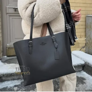 La Coach Mollie Tote Bag es una cartera mediana diseñada para mujeres que buscan funcionalidad, elegancia y organización en su día a día. Confeccionada en cuero doble faz, su acabado transmite una calidez natural y un look sofisticado que se adapta fácilmente a contextos laborales y urbanos. Su interior espacioso permite llevar cómodamente un notebook, documentos, cartera, maquillaje y otros esenciales, convirtiéndola en una excelente opción para el trabajo o jornadas largas fuera de casa. Incorpora un cierre superior con cremallera que mantiene tus pertenencias seguras, además de compartimentos laterales abiertos que facilitan el acceso rápido a lo que más usas. En el interior cuenta con bolsillos multifunción, ideales para mantener todo organizado. Las asas con caída de 10,25” permiten llevarla cómodamente al hombro durante todo el día. Medidas del modelo: Largo: 33,7 cm Alto: 28 cm Ancho: 12,7 cm Detalles del producto: Modelo: Mollie Tote Bag Marca: Coach Material: Cuero doble faz Forro: Tela Cierre: Cremallera superior Compartimentos: bolsillo interior multifunción y compartimentos laterales abiertos Estilo: Tote mediana, ideal para trabajo En Trendstore Chile encuentras carteras Coach 100% originales, con compra segura, atención cercana y envíos a todo Chile. Una cartera práctica, elegante y versátil, pensada para acompañarte todos los días.