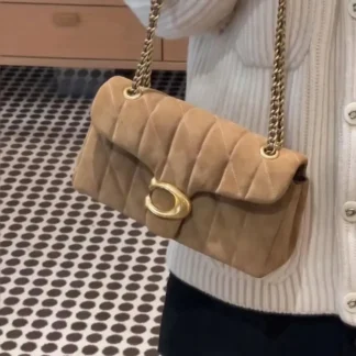 Este bolso de hombro Coach disponible en Trendstore Chile combina diseño atemporal y funcionalidad en una pieza pensada para mujeres que buscan estilo y practicidad. Su exterior está confeccionado en gamuza de alta calidad, con forro interior de lona resistente, logrando un equilibrio perfecto entre elegancia y durabilidad. El diseño presenta una parte superior con solapa y cierre de botón magnético, destacando los herrajes Coach en tono dorado en el frente. Cuenta con dos compartimentos bien distribuidos, incluyendo un compartimento central con cierre de cremallera, un compartimento interior deslizante con solapa magnética y un práctico bolsillo trasero también con cierre magnético, ideal para acceder fácilmente a lo esencial. La correa de hombro con cadena plateada deslizante permite adaptarlo a distintos estilos de uso, con una caída regulable entre 25 cm y 55 cm, ofreciendo comodidad y versatilidad. Sus dimensiones aproximadas son 26 cm de ancho, 13 cm de alto y 8 cm de profundidad, un tamaño ideal para el uso diario o salidas especiales. Un bolso original Coach, fabricado en Vietnam, pensado para mujeres que valoran la moda premium y los detalles bien logrados. Disponible en Trendstore Chile, tu tienda de confianza en accesorios de marcas originales.