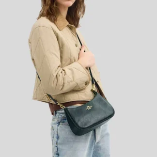 La cartera Teri Shoulder Bag de Coach en versión acolchada es una pieza elegante y versátil, ideal para mujeres que buscan un bolso sofisticado con un diseño contemporáneo. Disponible en Trendstore Chile, este modelo en color dark teal combina profundidad de color con un acabado refinado. Confeccionada en cuero liso brillante, su diseño acolchado aporta textura y un look moderno, manteniendo la esencia elegante de la marca. Es una opción perfecta tanto para el día como para salidas más especiales. Su interior funcional incluye un bolsillo multifunción que permite organizar tus esenciales, mientras que el cierre superior con cremallera asegura tus pertenencias. Incluye asa corta desmontable para llevar al hombro y correa larga ajustable que permite usarla cruzada, adaptándose a distintos estilos y ocasiones. Detalles del producto: Tipo: bolso de hombro / crossbody mujer Material: cuero liso brillante acolchado Forro: tela Medidas: 24,1 cm (largo) x 15,2 cm (alto) x 7,6 cm (ancho) Asa corta desmontable: 21,6 cm Correa desmontable: 57,8 cm Cierre superior con cremallera Interior: bolsillo multifunción Herrajes en tono dorado Color: dark teal Código de producto: CDP32 En Trendstore Chile ofrecemos productos 100% originales, con compra segura y envíos a todo Chile.