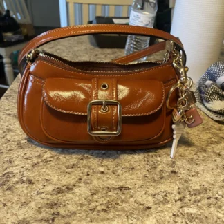La cartera Ashton Mini Shoulder Bag de Coach es una pieza moderna, compacta y sofisticada, ideal para mujeres que buscan un bolso pequeño con estilo único. Disponible en Trendstore Chile, este modelo en tono light violet destaca por su acabado suave y femenino.
