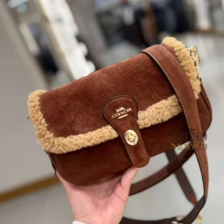 La cartera Hadley Shoulder Bag de Coach es una pieza elegante y distintiva, diseñada para mujeres que buscan un accesorio sofisticado con carácter. Disponible en Trendstore Chile, este modelo en tono vintage brown combina materiales premium con un diseño moderno y versátil. Está confeccionada en gamuza y shearling, logrando una combinación de texturas que aporta profundidad visual, calidez y un estilo único. Su acabado la convierte en una opción ideal para temporadas más frías o para quienes buscan destacar con un bolso diferente. El diseño incorpora cierre tipo turnlock, que aporta seguridad y un detalle icónico de la marca. En su interior, cuenta con bolsillos multifuncionales que permiten organizar fácilmente tus esenciales, mientras que el bolsillo exterior abierto facilita el acceso rápido. Incluye asa corta desmontable y correa larga ajustable y desmontable, permitiendo usarla al hombro o cruzada según tu estilo o necesidad. Detalles del producto: Tipo: bolso de hombro / crossbody mujer Material exterior: gamuza y shearling Forro: tela Medidas: 24,8 cm (ancho) x 15,2 cm (alto) x 7 cm (profundidad) Asa corta desmontable: 24,1 cm Correa larga desmontable: 50,8 cm Cierre tipo turnlock Bolsillo exterior abierto Interior: bolsillos multifuncionales Color: vintage brown multi Código de producto: CDL68 En Trendstore Chile ofrecemos productos 100% originales, con compra segura y envíos a todo Chile.