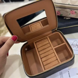 El Coach Large Jewelry Box en Signature Canvas es un accesorio sofisticado y funcional, ideal para organizar tus joyas con elegancia. Disponible en Trendstore Chile, este modelo combina el diseño icónico de la marca con una estructura compacta y práctica. Confeccionado en lona recubierta tipo PVC con estampado Signature, ofrece resistencia, durabilidad y fácil limpieza. Su formato compacto lo hace perfecto tanto para uso diario como para llevar en viajes, manteniendo tus accesorios protegidos y organizados. Cuenta con cierre superior con cremallera para mayor seguridad. En su interior, incluye múltiples compartimentos diseñados para distintas piezas: espacio para anillos, espejo integrado y compartimentos libres para guardar collares, aros u otros accesorios. Su diseño elegante lo convierte también en una excelente opción de regalo. Detalles del producto: Tipo: joyero / organizador de joyas Material: lona recubierta PVC con estampado Signature Medidas: 12,7 cm (largo) x 10,2 cm (alto) x 5,1 cm (profundidad) Cierre superior con cremallera Interior: 7 espacios para anillos Incluye espejo interior 3 compartimentos libres Diseño compacto y portátil En Trendstore Chile ofrecemos productos 100% originales, con compra segura y envíos a todo Chile.