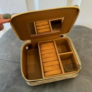 El Coach Large Jewelry Box en Signature Canvas es un accesorio sofisticado y funcional, ideal para organizar tus joyas con elegancia. Disponible en Trendstore Chile, este modelo combina el diseño icónico de la marca con una estructura compacta y práctica. Confeccionado en lona recubierta tipo PVC con estampado Signature, ofrece resistencia, durabilidad y fácil limpieza. Su formato compacto lo hace perfecto tanto para uso diario como para llevar en viajes, manteniendo tus accesorios protegidos y organizados. Cuenta con cierre superior con cremallera para mayor seguridad. En su interior, incluye múltiples compartimentos diseñados para distintas piezas: espacio para anillos, espejo integrado y compartimentos libres para guardar collares, aros u otros accesorios. Su diseño elegante lo convierte también en una excelente opción de regalo. Detalles del producto: Tipo: joyero / organizador de joyas Material: lona recubierta PVC con estampado Signature Medidas: 12,7 cm (largo) x 10,2 cm (alto) x 5,1 cm (profundidad) Cierre superior con cremallera Interior: 7 espacios para anillos Incluye espejo interior 3 compartimentos libres Diseño compacto y portátil En Trendstore Chile ofrecemos productos 100% originales, con compra segura y envíos a todo Chile.