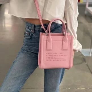 Cartera Marc Jacobs Small Standard Supply Tote de cuero rosa original disponible en Trendstore Chile. Vista frontal de la cartera Marc Jacobs Small Standard Supply Tote rosa con compra segura y envío a todo Chile. Detalle del cuero premium de la cartera Marc Jacobs Standard Supply Tote original disponible en Trendstore Chile. Vista lateral de la cartera Marc Jacobs Small Standard Supply Tote rosa con correa ajustable y desmontable. Interior de la cartera Marc Jacobs Small Standard Supply Tote de cuero disponible en Trendstore Chile. Cartera Marc Jacobs Standard Supply Tote rosa original para mujer con despacho a todo Chile desde Trendstore Chile. Detalle de las asas superiores y acabados premium de la Marc Jacobs Small Standard Supply Tote original. Cartera Marc Jacobs Small Standard Supply Tote de cuero rosa original, compra segura y envío a todo Chile desde Trendstore Chile.