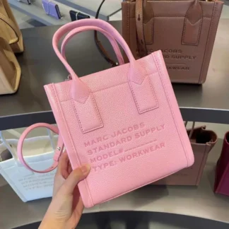 Cartera Marc Jacobs Small Standard Supply Tote de cuero rosa original disponible en Trendstore Chile. Vista frontal de la cartera Marc Jacobs Small Standard Supply Tote rosa con compra segura y envío a todo Chile. Detalle del cuero premium de la cartera Marc Jacobs Standard Supply Tote original disponible en Trendstore Chile. Vista lateral de la cartera Marc Jacobs Small Standard Supply Tote rosa con correa ajustable y desmontable. Interior de la cartera Marc Jacobs Small Standard Supply Tote de cuero disponible en Trendstore Chile. Cartera Marc Jacobs Standard Supply Tote rosa original para mujer con despacho a todo Chile desde Trendstore Chile. Detalle de las asas superiores y acabados premium de la Marc Jacobs Small Standard Supply Tote original. Cartera Marc Jacobs Small Standard Supply Tote de cuero rosa original, compra segura y envío a todo Chile desde Trendstore Chile.