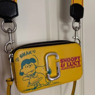 Cartera Marc Jacobs The Snapshot x Peanuts Snoopy & Lucy de cuero Saffiano original disponible en Trendstore Chile. Vista frontal de la cartera Marc Jacobs Snapshot Peanuts con estampado Snoopy y Lucy, compra segura en Chile. Detalle del estampado Snoopy & Lucy y logo Double J de la cartera Marc Jacobs original en Trendstore Chile. Vista lateral de la Marc Jacobs The Snapshot x Peanuts con correa exclusiva Snoopy y envío a todo Chile. Interior de la cartera Marc Jacobs Snapshot Peanuts con doble compartimento disponible en Trendstore Chile. Cartera crossbody Marc Jacobs x Peanuts de cuero Saffiano original para mujer con despacho a todo Chile. Textura del cuero Saffiano premium de la Marc Jacobs Snapshot Snoopy & Lucy original en Trendstore Chile. Cartera Marc Jacobs The Snapshot x Peanuts original, edición especial con compra segura y envío a todo Chile desde Trendstore Chile.