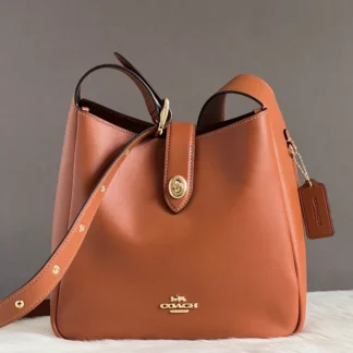 Cartera Coach Hadley Convertible Crossbody Gold Tan de cuero original disponible en Trendstore Chile. Vista frontal de la Coach Hadley Gold Tan de cuero con cierre Turnlock y compra segura en Chile. Detalle del cuero de grano liso de la cartera Coach Hadley Convertible Crossbody original. Vista lateral de la Coach Hadley Gold Tan con correa ajustable para hombro o crossbody. Interior de la cartera Coach Hadley con bolsillo de cremallera disponible en Trendstore Chile. Cartera Coach Hadley de cuero original para mujer con despacho y envío a todo Chile. Detalle del cierre Turnlock y acabados premium de la Coach Hadley Gold Tan original. Coach Hadley Convertible Crossbody Gold Tan original, compra segura y envío a todo Chile desde Trendstore Chile.