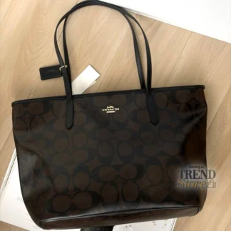 Cartera Coach Large City Tote Maxi Signature Canvas Gold Walnut Black original disponible en Trendstore Chile. Vista frontal de la Coach Large City Tote con monograma Maxi Signature y compra segura en Chile. Detalle del Signature Coated Canvas de la cartera Coach Large City Tote original en Trendstore Chile. Vista lateral de la Coach Large City Tote Walnut Black de gran capacidad con envío a todo Chile. Interior de la cartera Coach Large City Tote con bolsillo y cierre de cremallera disponible en Trendstore Chile. Cartera tote Coach Maxi Signature original para mujer, modelo amplio premium con despacho a todo Chile. Detalle del monograma Maxi Signature y terminaciones de la Coach Large City Tote original en Trendstore Chile. Coach Large City Tote Gold Walnut Black original con compra segura y envío a todo Chile desde Trendstore Chile.